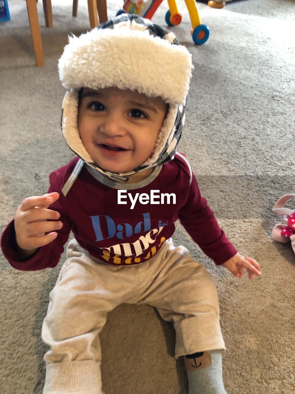 Portrait of cute smiling boy sitting on rug at home