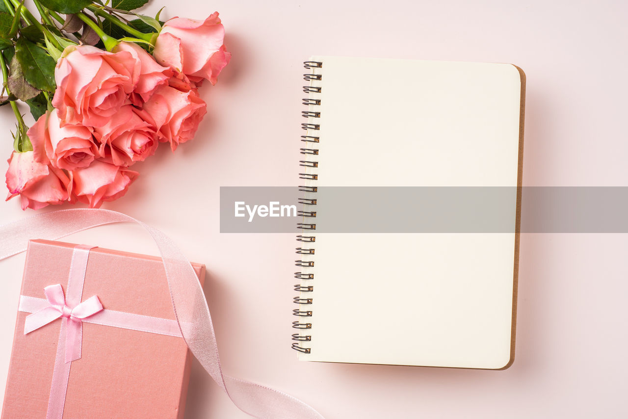 HIGH ANGLE VIEW OF ROSE ON BOOK