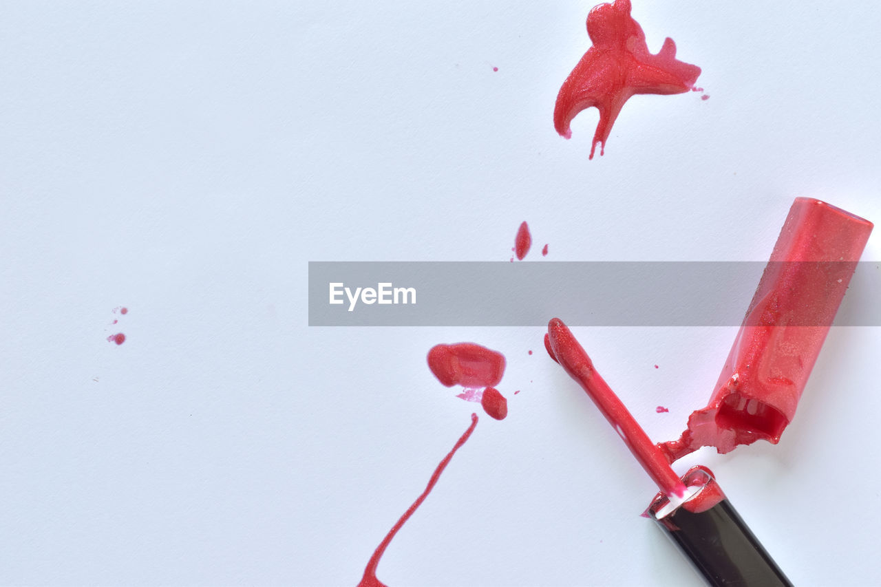 High angle view of red broken lipstick against white background