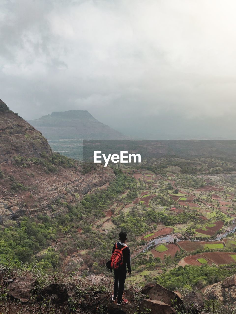 Rear view of man standing on mountain against sky