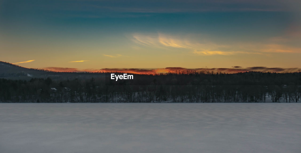 SNOW COVERED LANDSCAPE AGAINST SKY DURING SUNSET