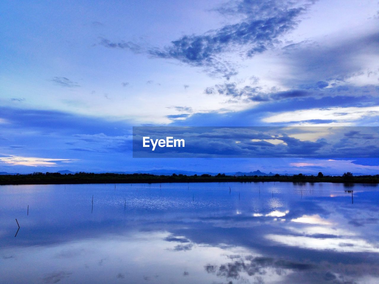 SCENIC VIEW OF CALM LAKE AGAINST CLOUDY SKY