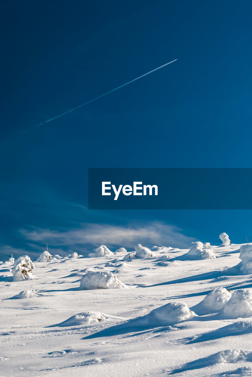 Snow covered landscape against blue sky