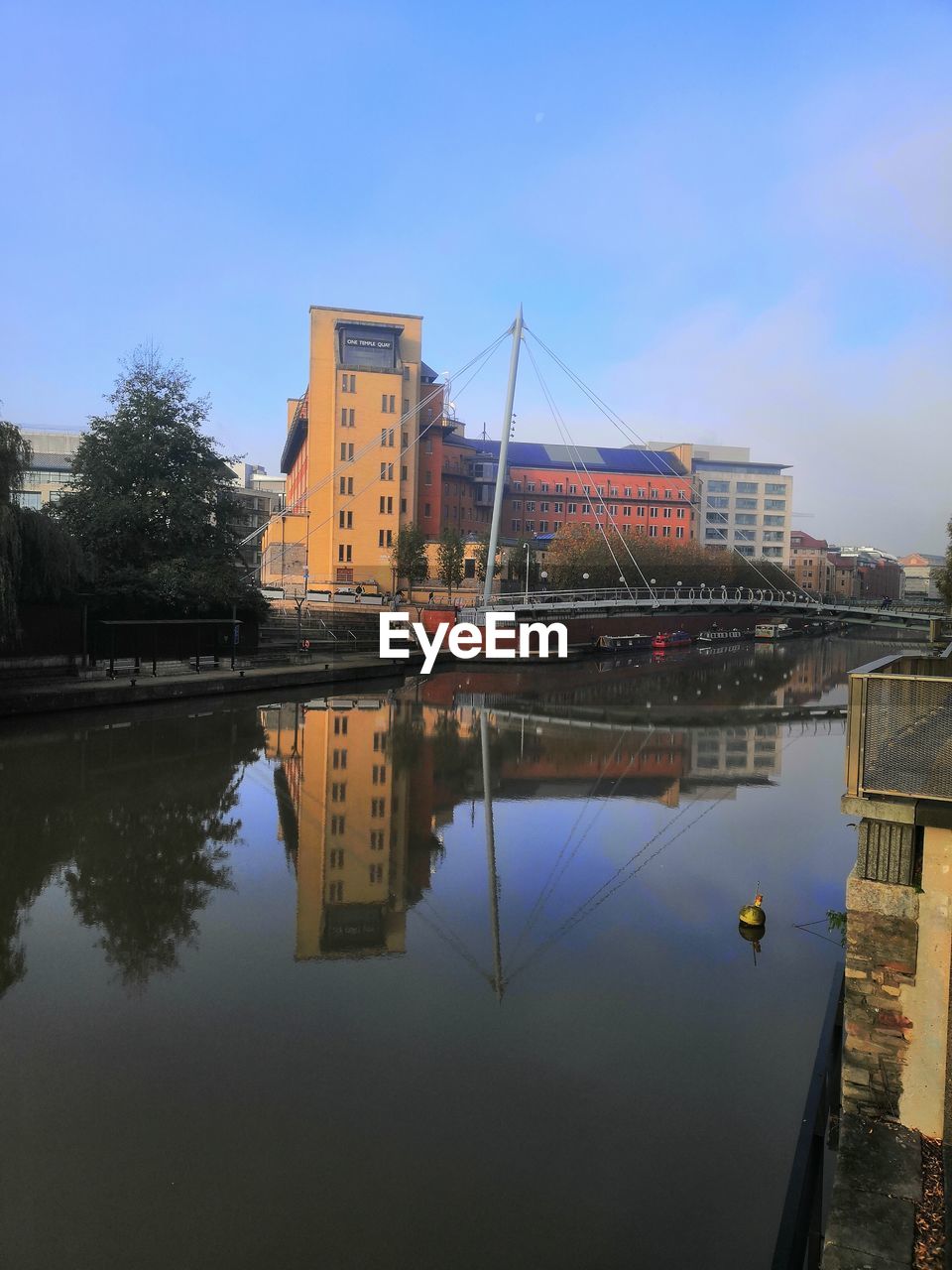 BRIDGE OVER RIVER AMIDST BUILDINGS AGAINST SKY