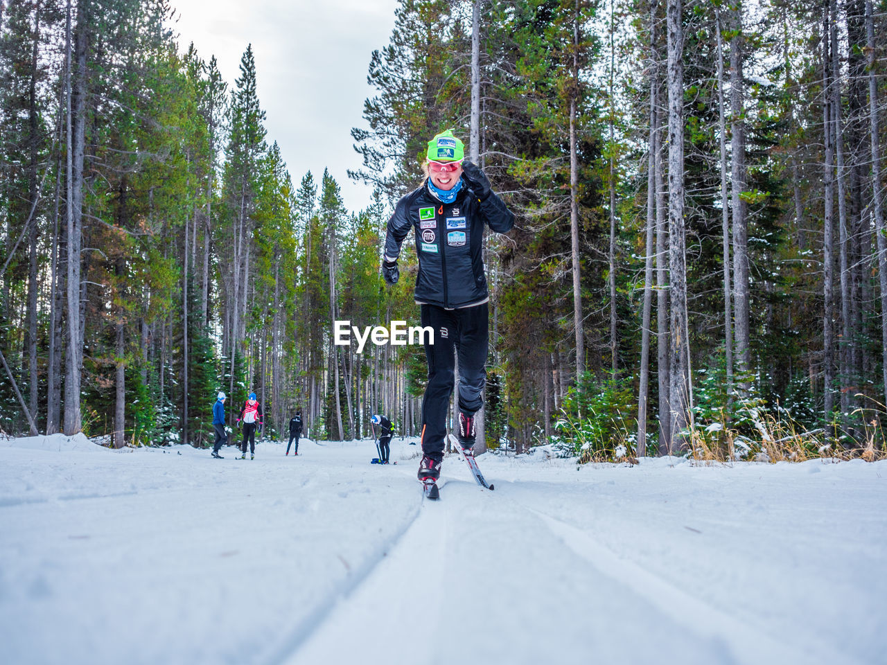 REAR VIEW OF WOMAN WALKING IN SNOW COVERED TREES