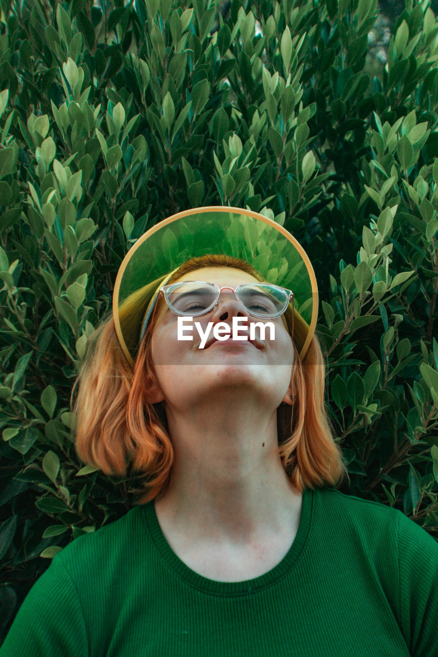 Smiling woman wearing sunglasses against plants