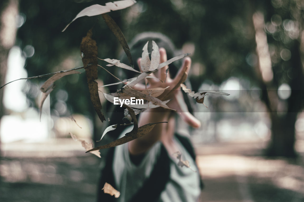 Woman throwing dry leaves in park