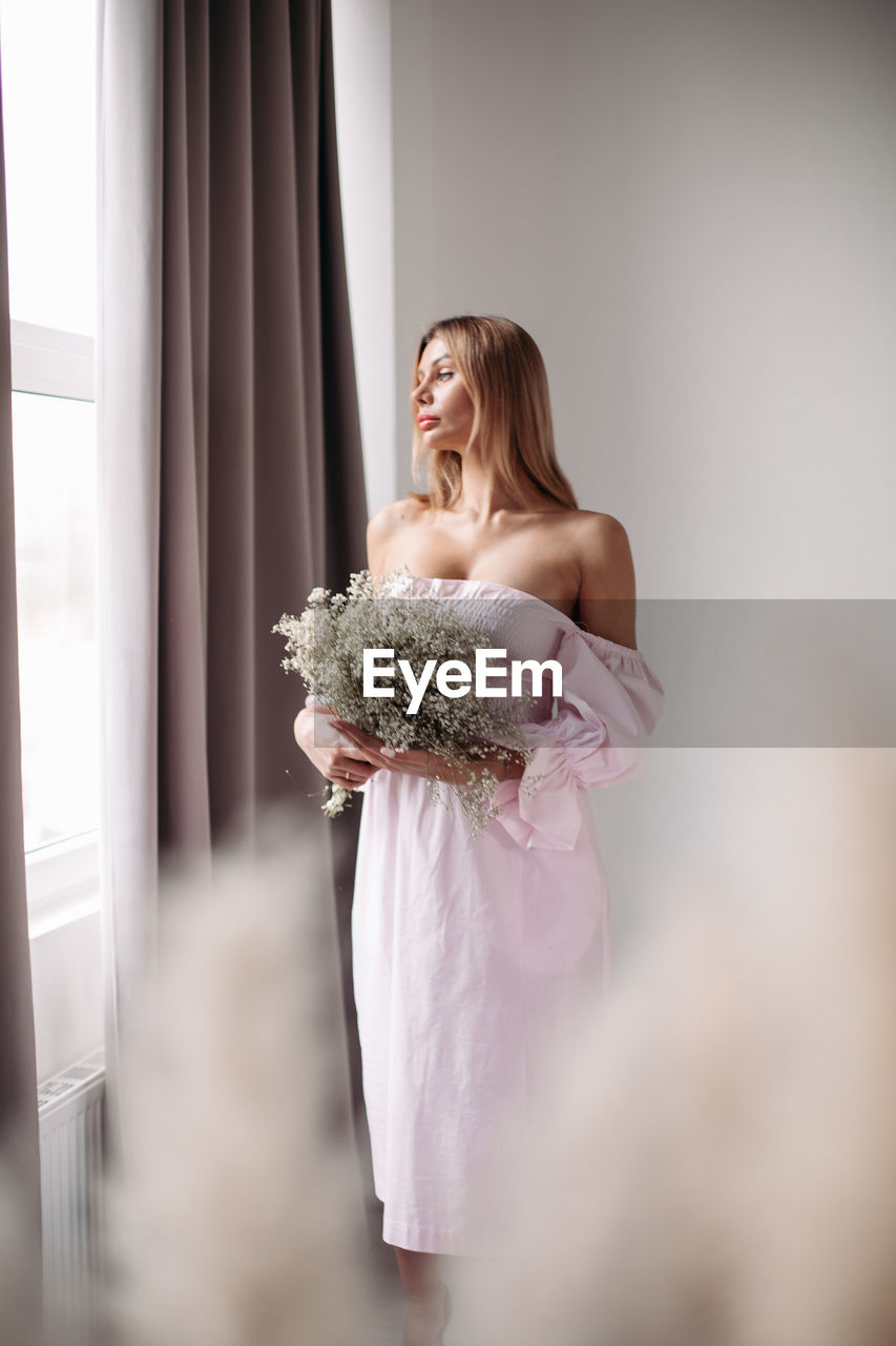 WOMAN STANDING BY PINK FLOWER