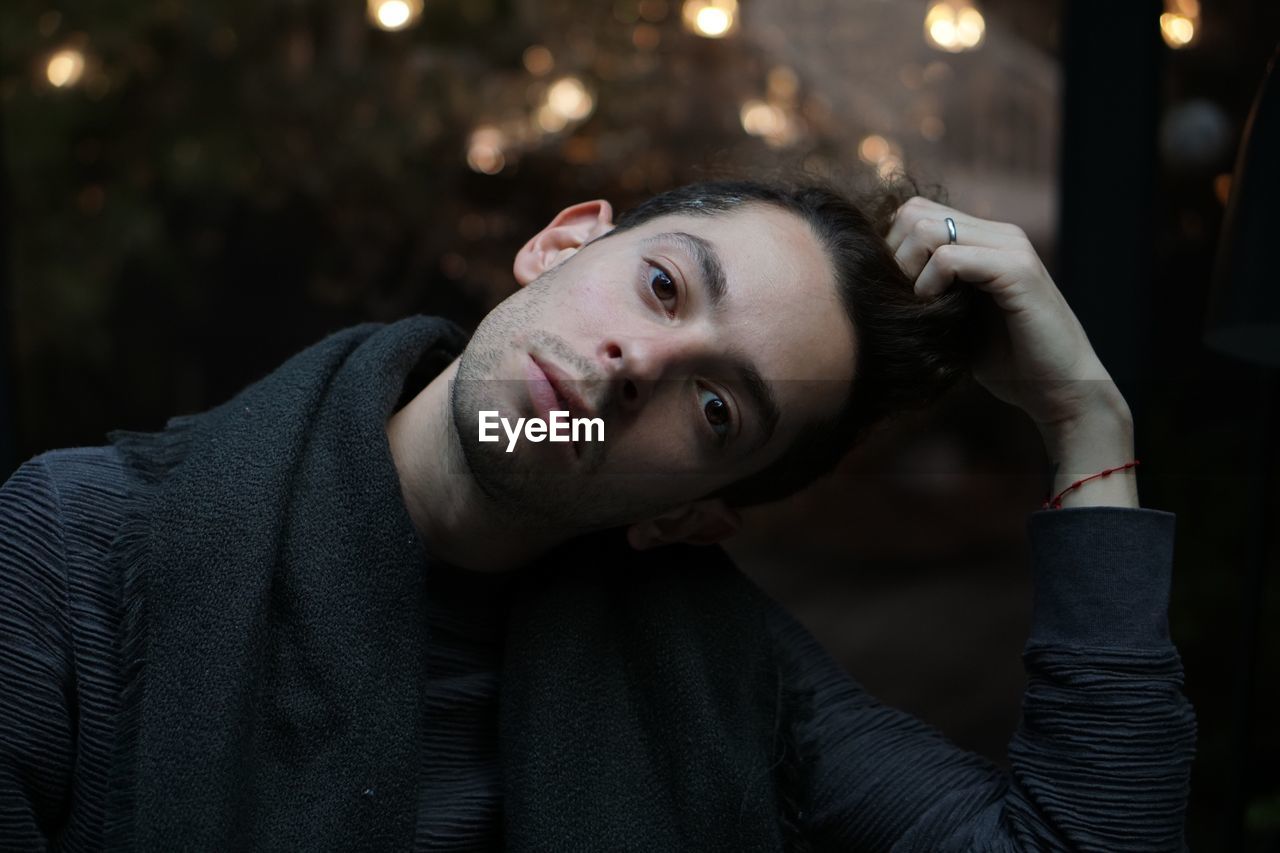 Portrait of young man with hand in hair wearing warm clothing