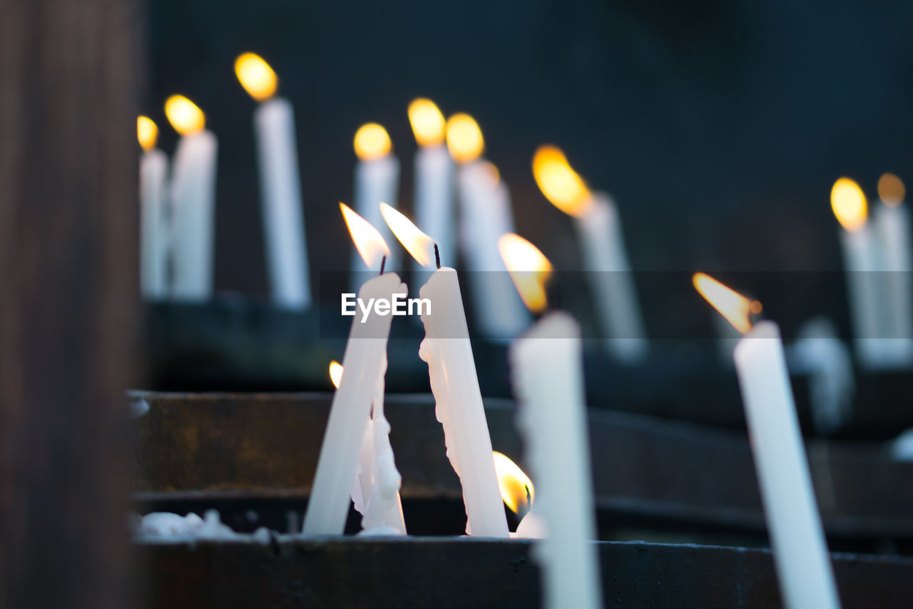 CLOSE-UP OF LIT CANDLES ON TEMPLE