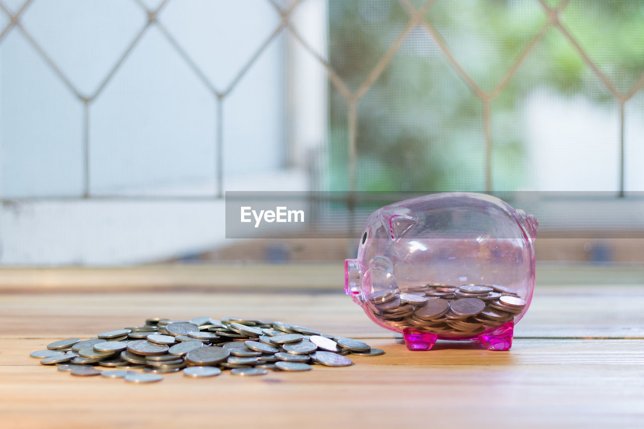 Close-up of piggy bank and coins on table