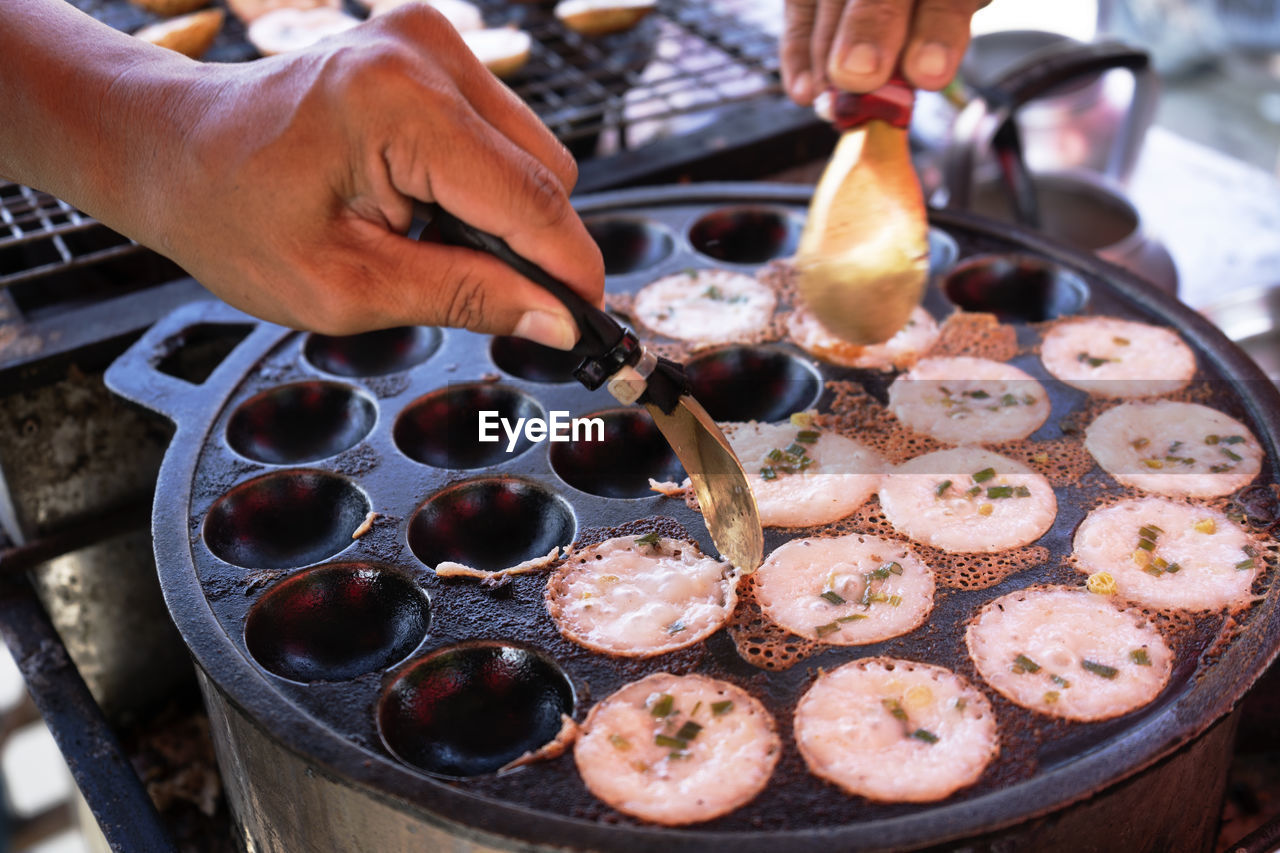 HIGH ANGLE VIEW OF PERSON PREPARING FOOD ON BARBECUE GRILL