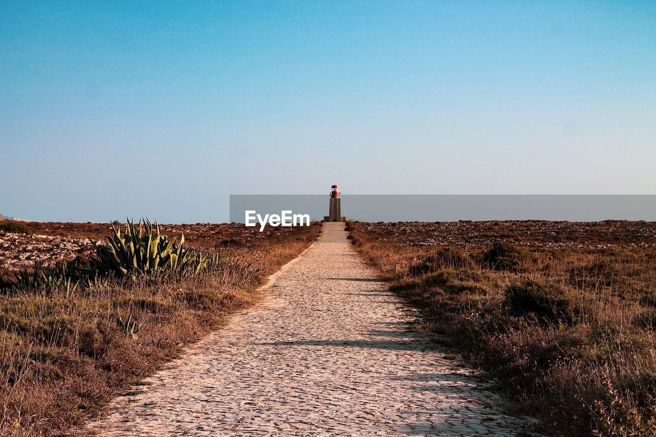 Lighthouse at coastline against clear sky