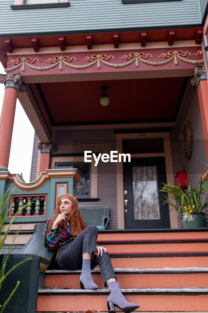 WOMAN SITTING OUTSIDE HOUSE