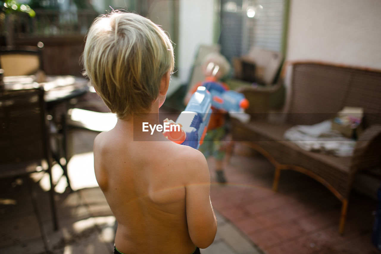 Brothers playing with water guns in front yard