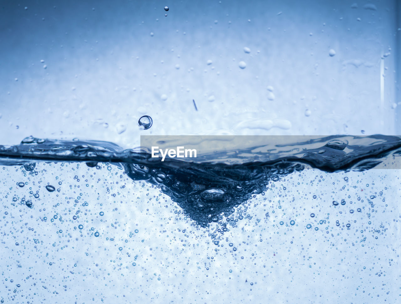 CLOSE-UP OF WET GLASS AGAINST BLUE BACKGROUND