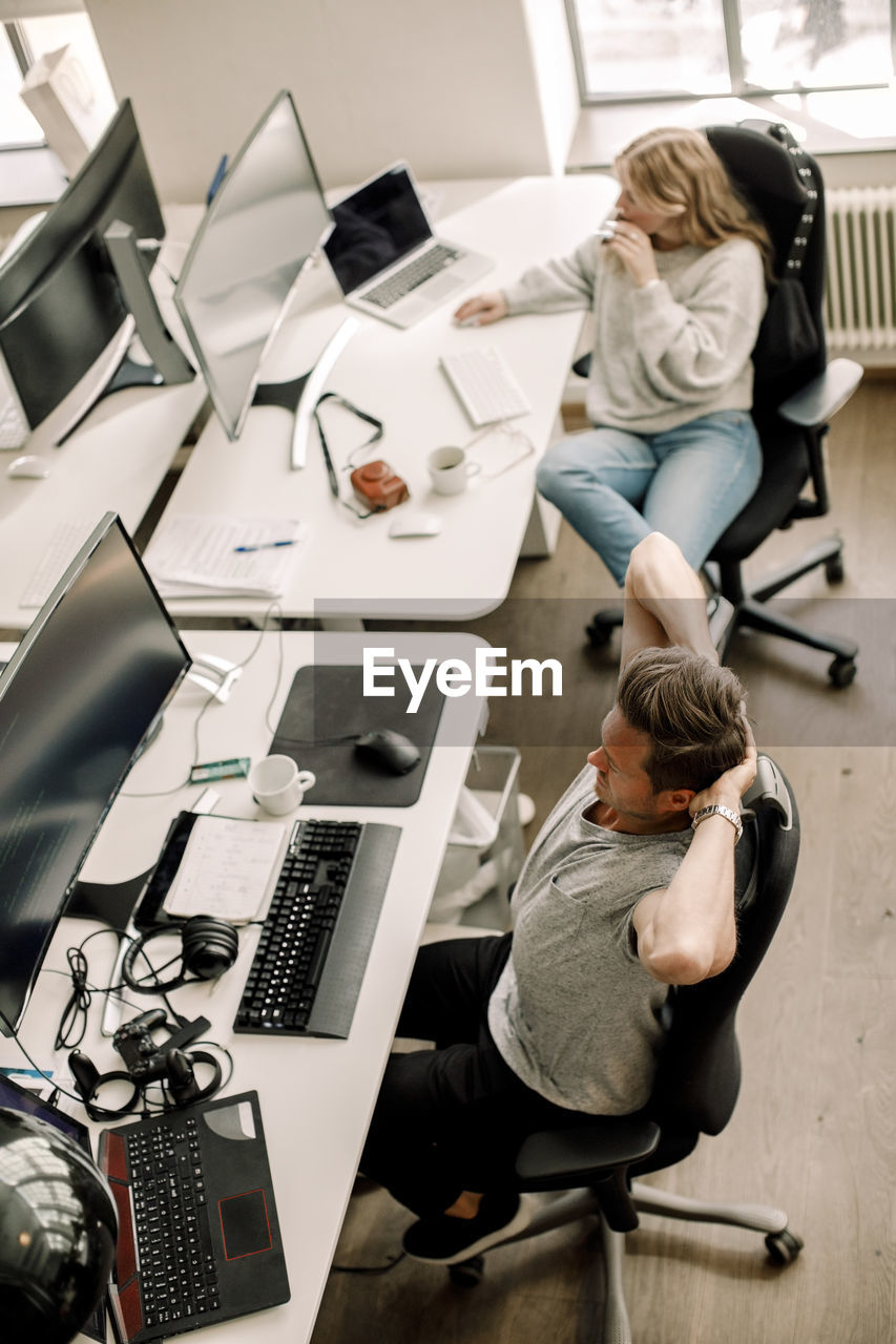 High angle view of male and female computer programmers sitting at table in office