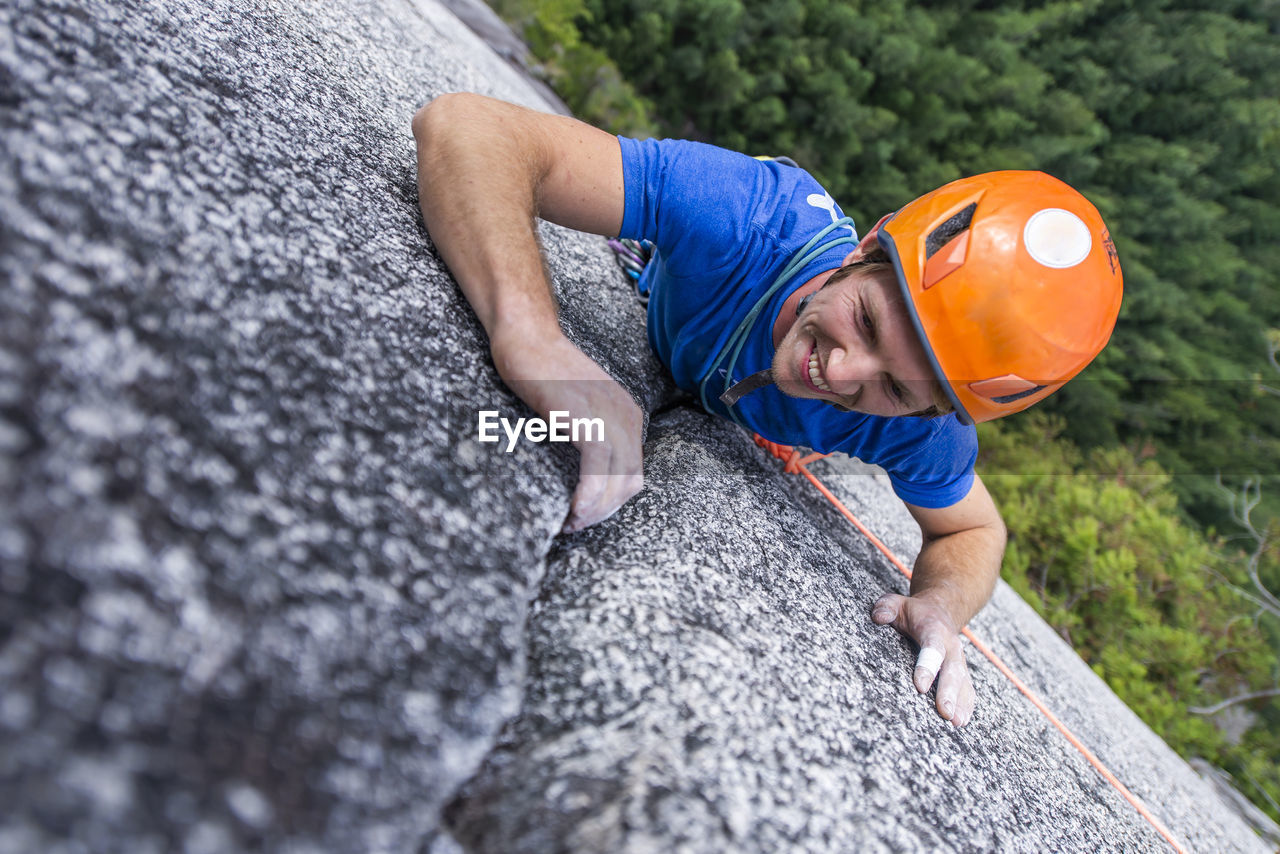 Climber looking up and laughing while rock climbing with helmet chief