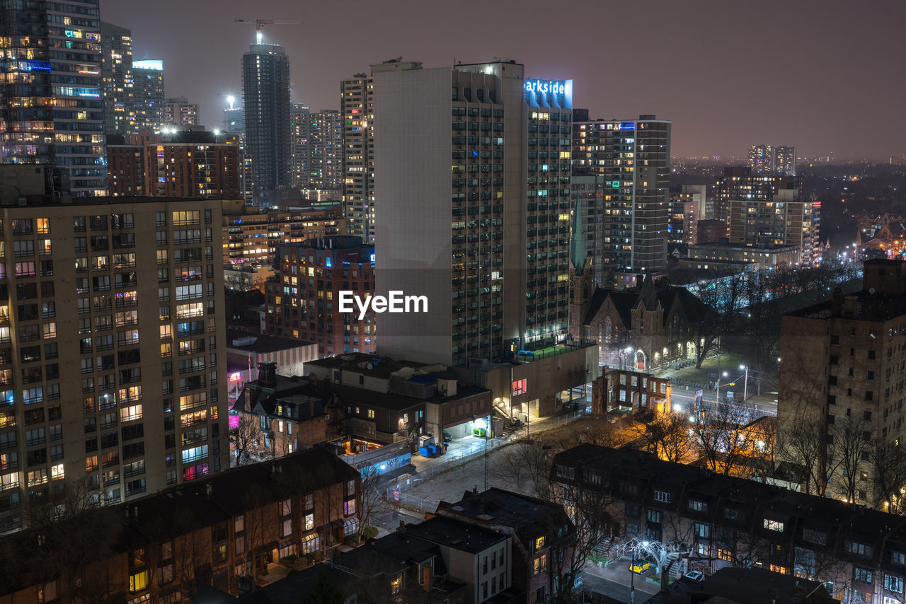 HIGH ANGLE VIEW OF ILLUMINATED BUILDINGS IN CITY AGAINST SKY