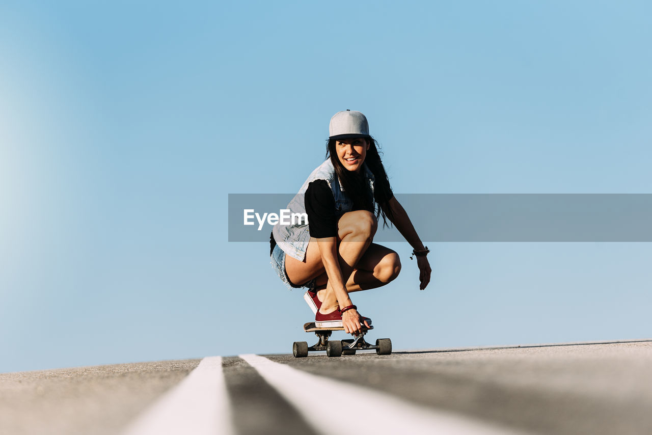 Woman skateboarding against blue sky