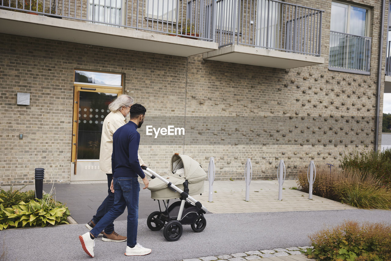 Men pushing pram in front of block of flats