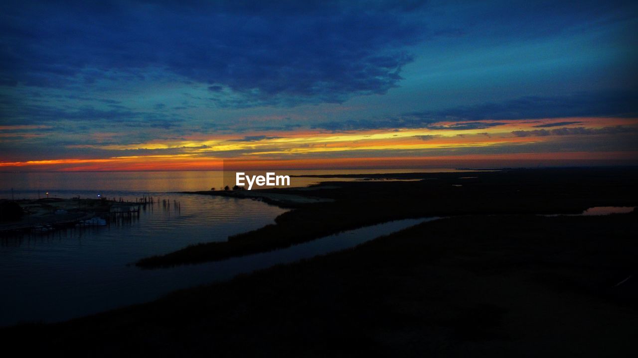 SCENIC VIEW OF BEACH AGAINST SKY AT SUNSET