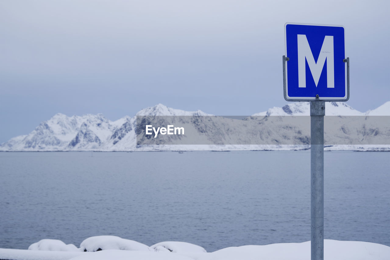 INFORMATION SIGN ON SNOWCAPPED MOUNTAIN AGAINST SKY