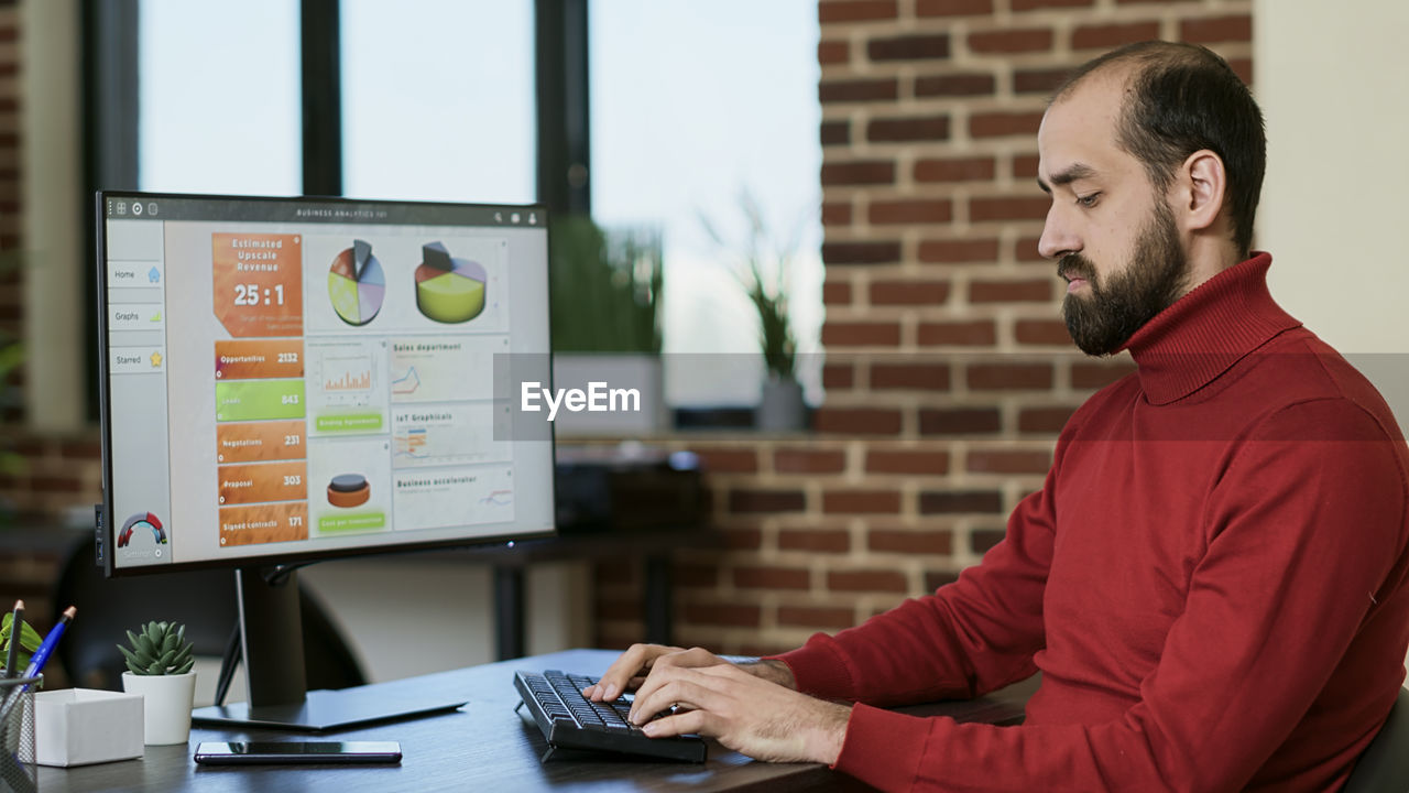 Young businessman using desktop pc at desk