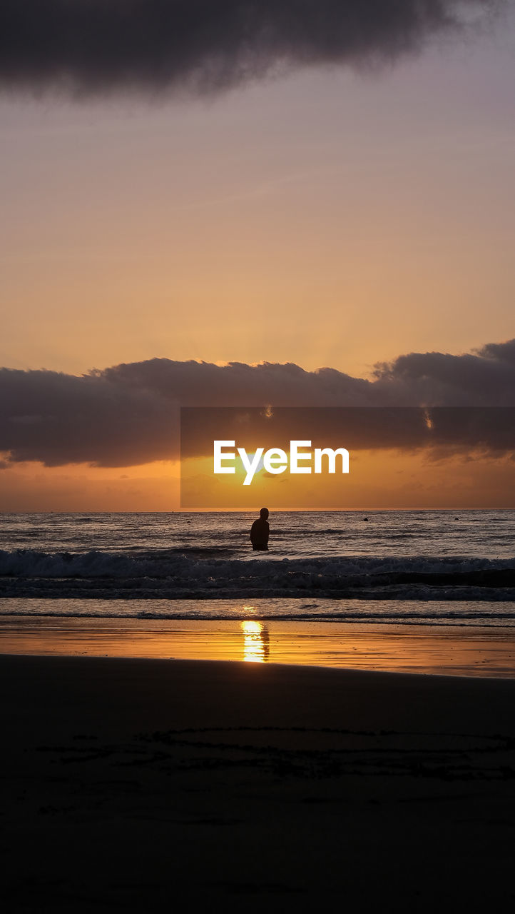 sky, sea, water, sunset, beach, land, beauty in nature, scenics - nature, silhouette, nature, horizon, cloud, orange color, tranquility, ocean, tranquil scene, one person, afterglow, reflection, dawn, body of water, coast, holiday, vacation, idyllic, trip, leisure activity, outdoors, horizon over water, lifestyles, motion, wave, sun, sports, travel destinations, sunlight, dramatic sky, travel, full length, mountain, men, shore, environment