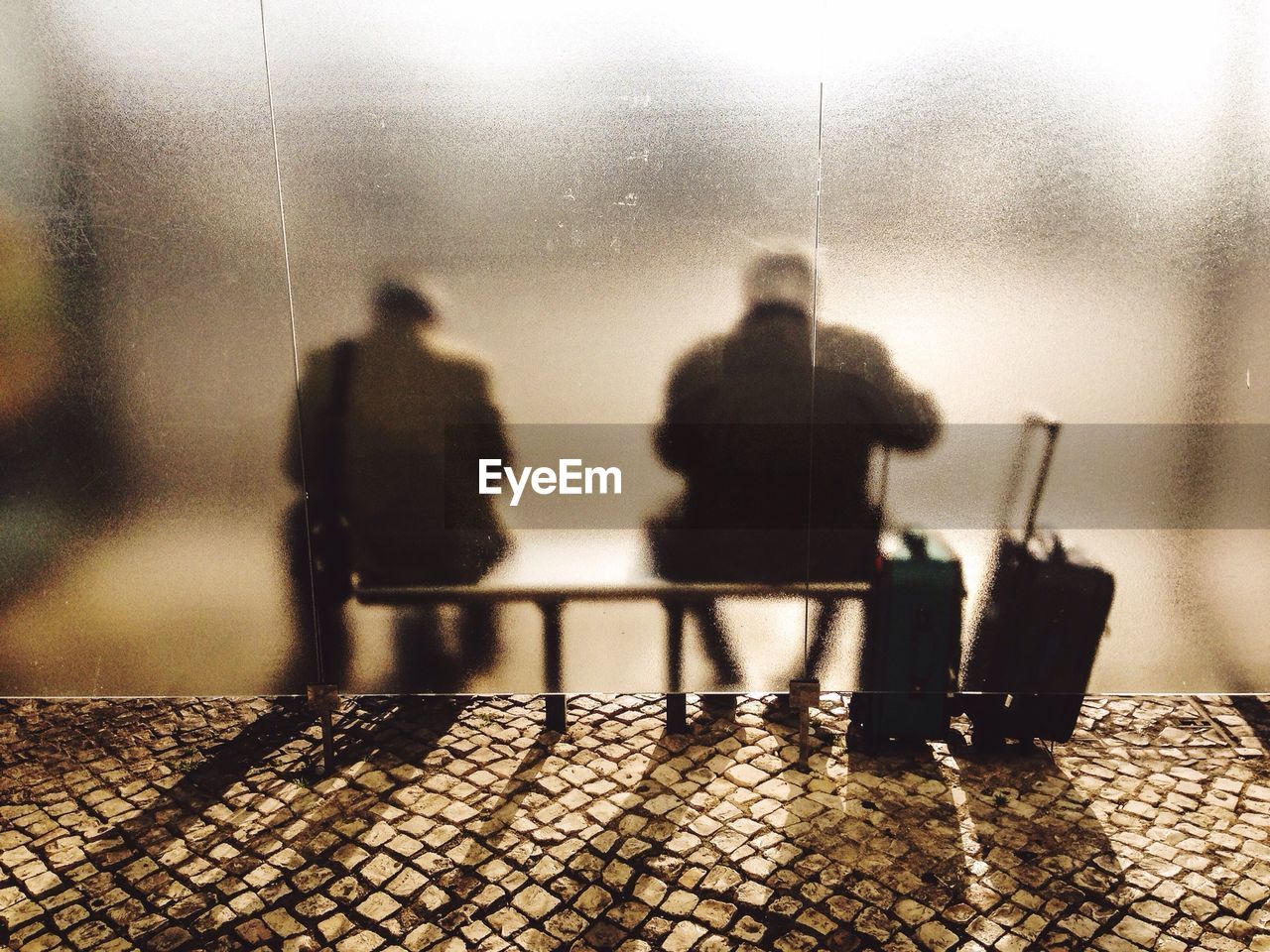 Rear view of two men sitting at bus stop