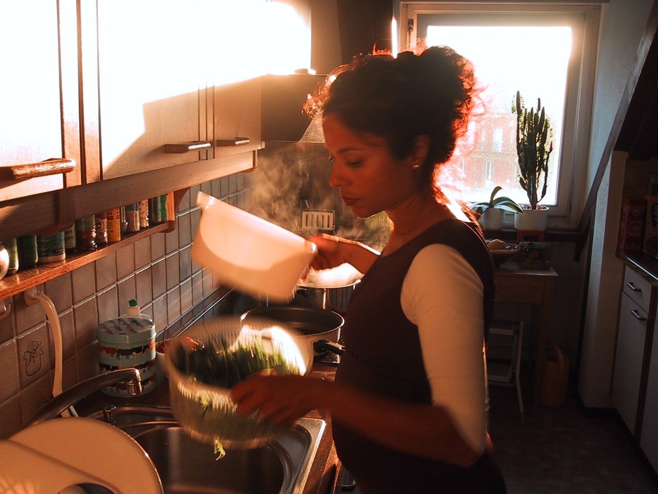 Young pregnant woman washing vegetables in kitchen