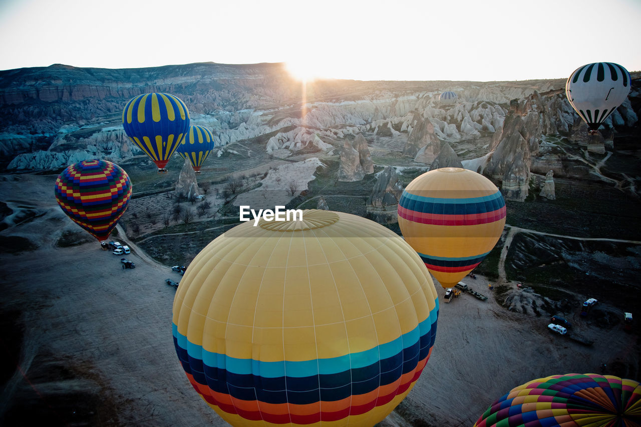 MULTI COLORED HOT AIR BALLOONS FLYING IN MOUNTAINS