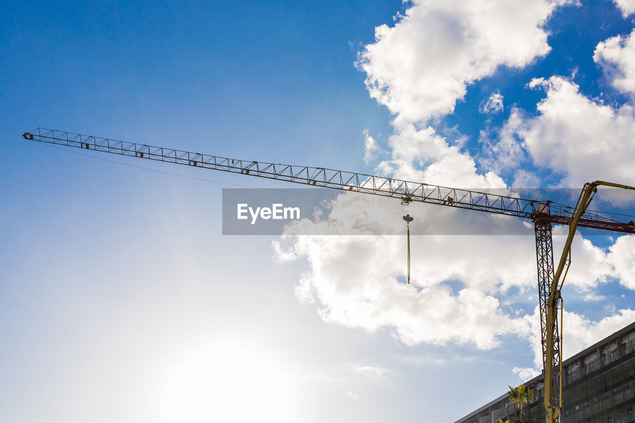 LOW ANGLE VIEW OF CRANES AGAINST SKY