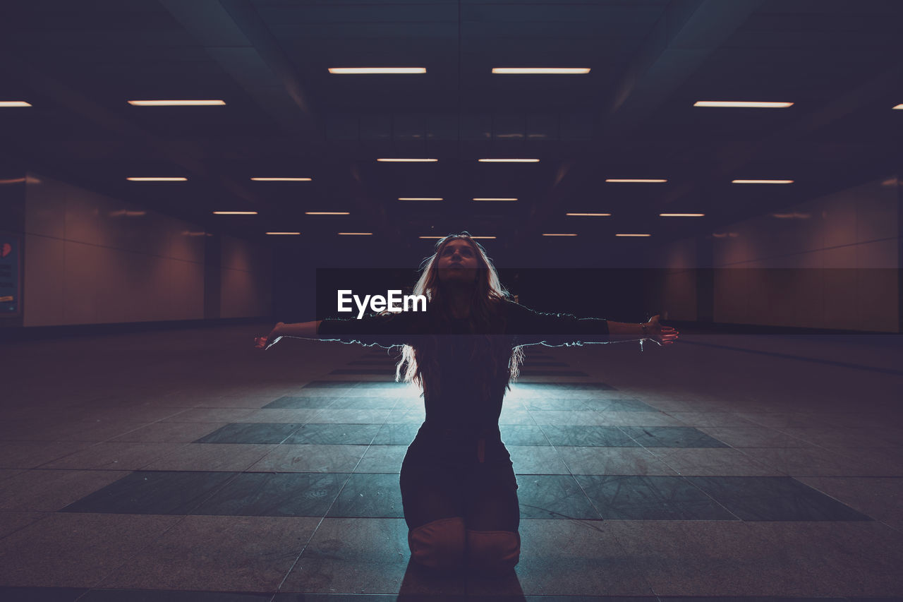 Young woman kneeling in underground walkway