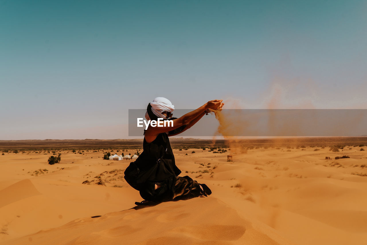 Full length side view of woman walking on sand dune