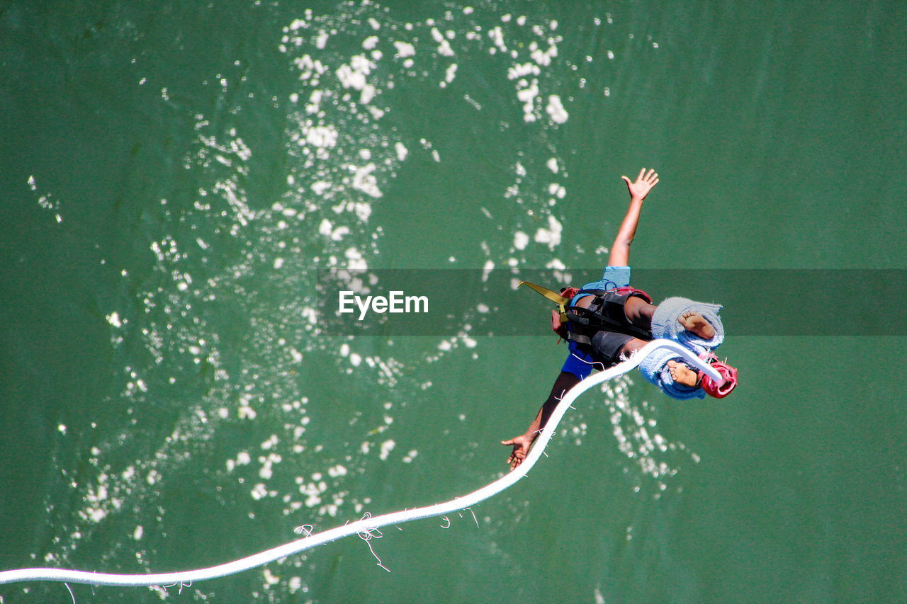 High angle view of man bungee jumping in river