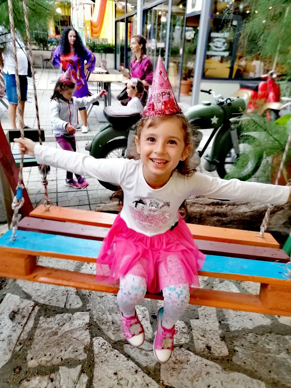 PORTRAIT OF CUTE GIRL SMILING WHILE SITTING ON WOOD