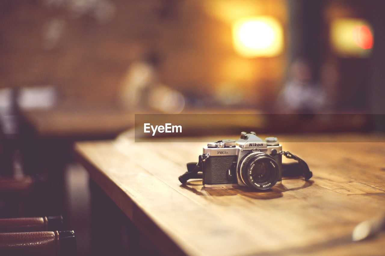 CLOSE-UP OF VINTAGE CAMERA ON TABLE AT HOME