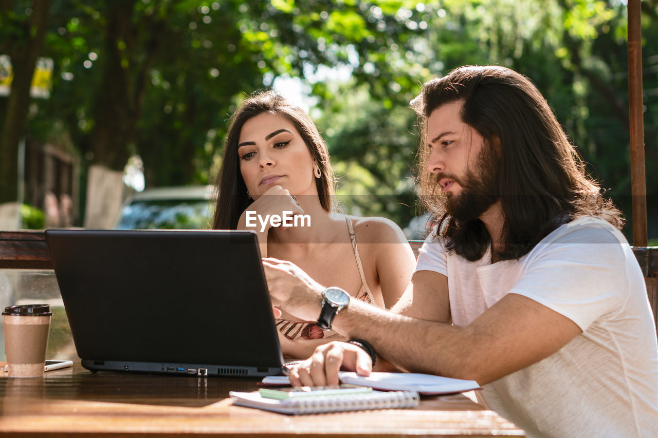 young woman using laptop while sitting on table