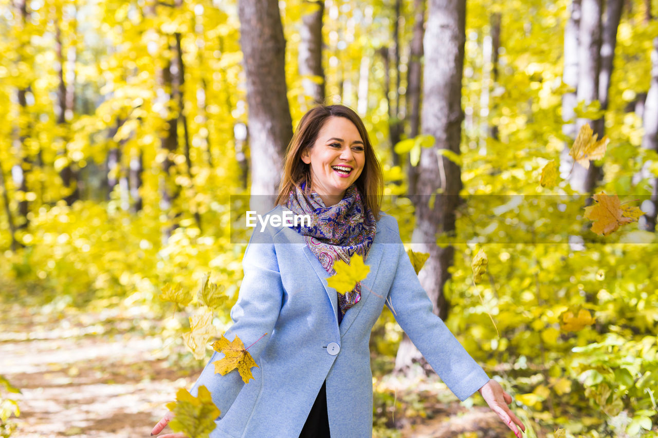 PORTRAIT OF A SMILING WOMAN STANDING IN FOREST