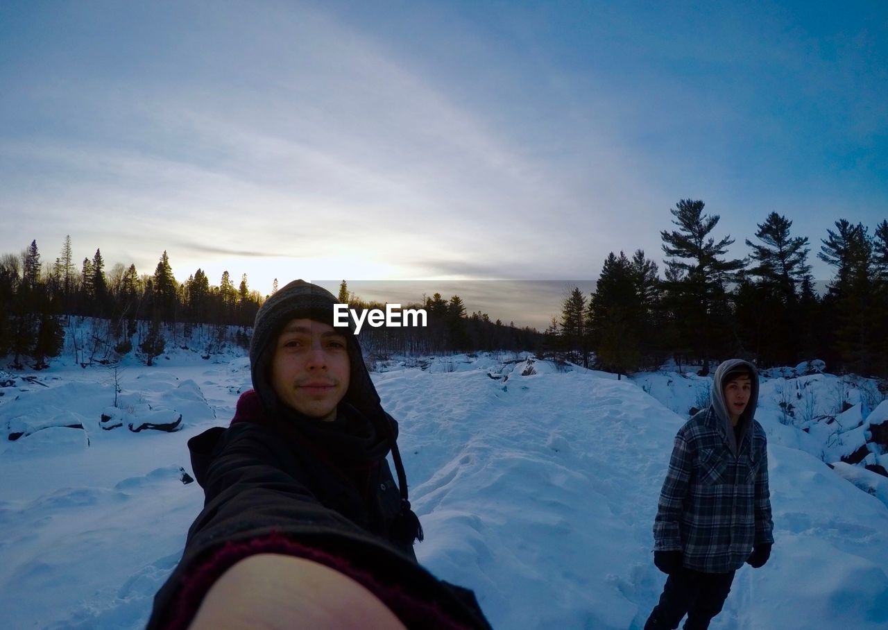 Portrait of man standing with friend on field during winter