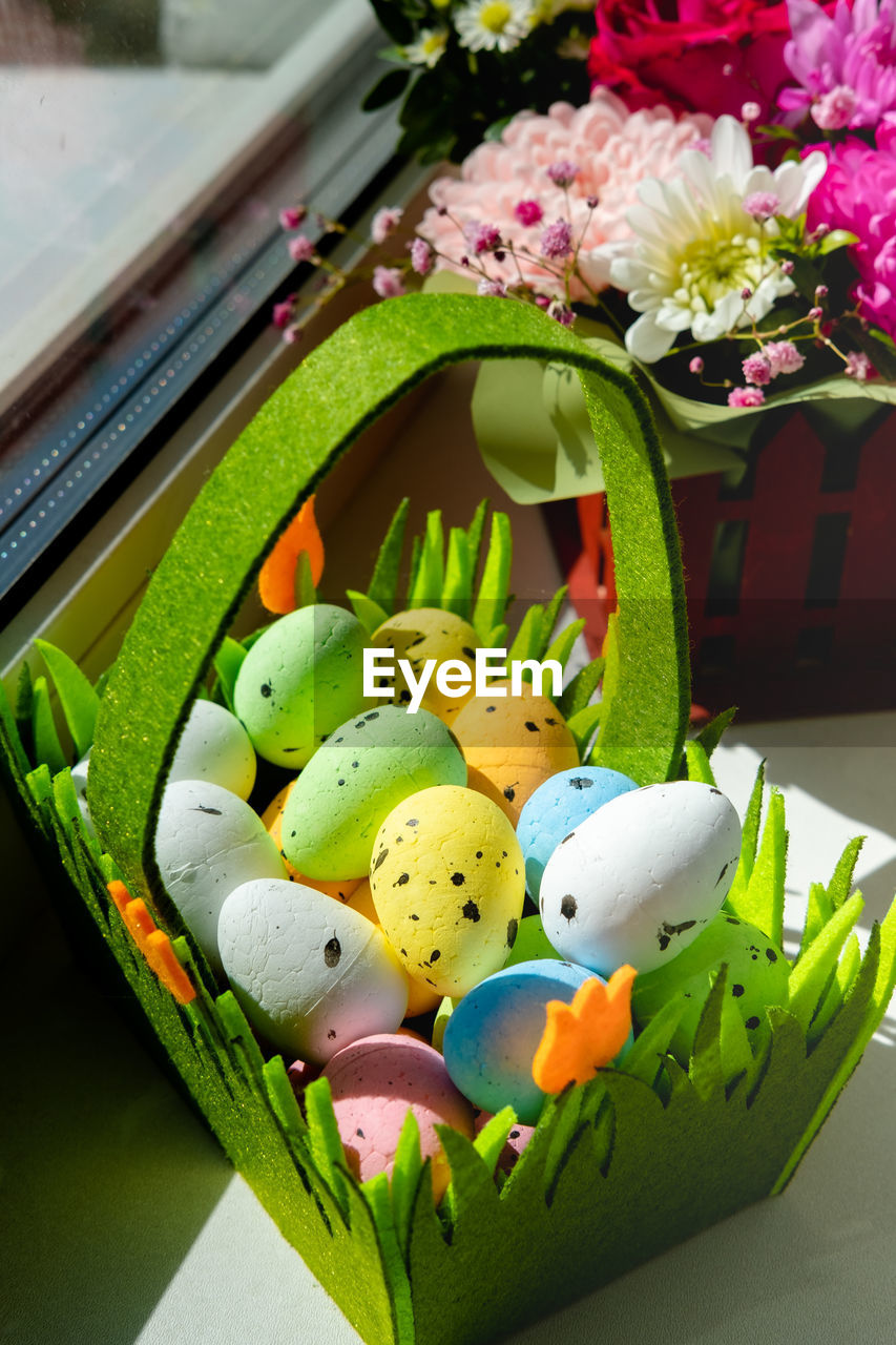 easter, flowering plant, flower, egg, easter egg, freshness, plant, green, floristry, multi colored, celebration, food, holiday, nature, no people, yellow, food and drink, tradition, decoration, container, indoors, still life, creativity, close-up, springtime, basket, animal representation, arrangement