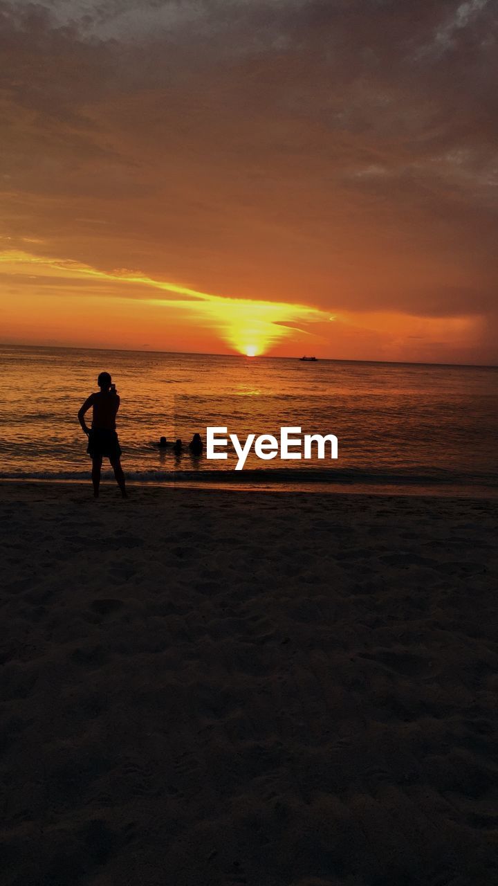 SILHOUETTE MAN ON BEACH AGAINST SKY DURING SUNSET