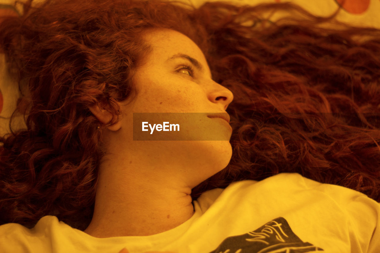 Close-up portrait of young redhead woman looking away