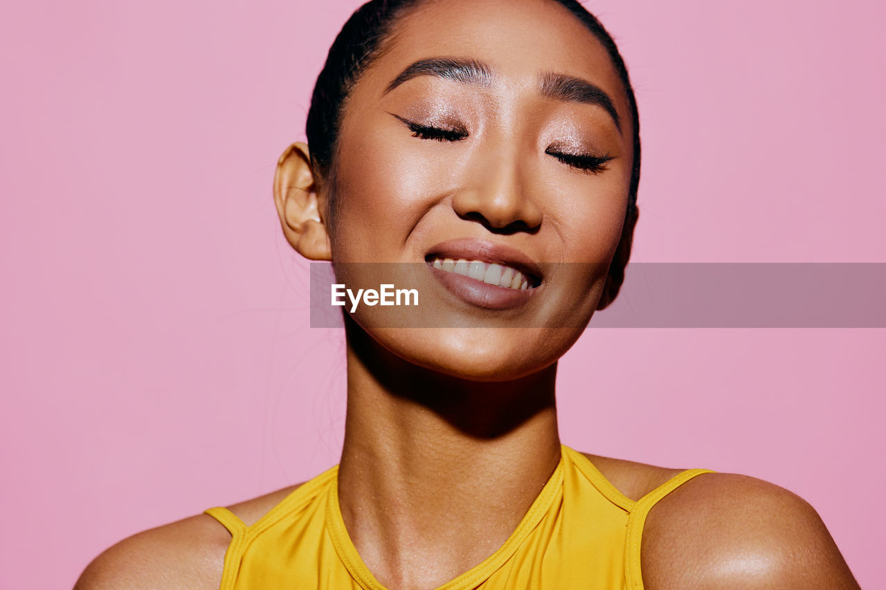 close-up portrait of young woman against pink background