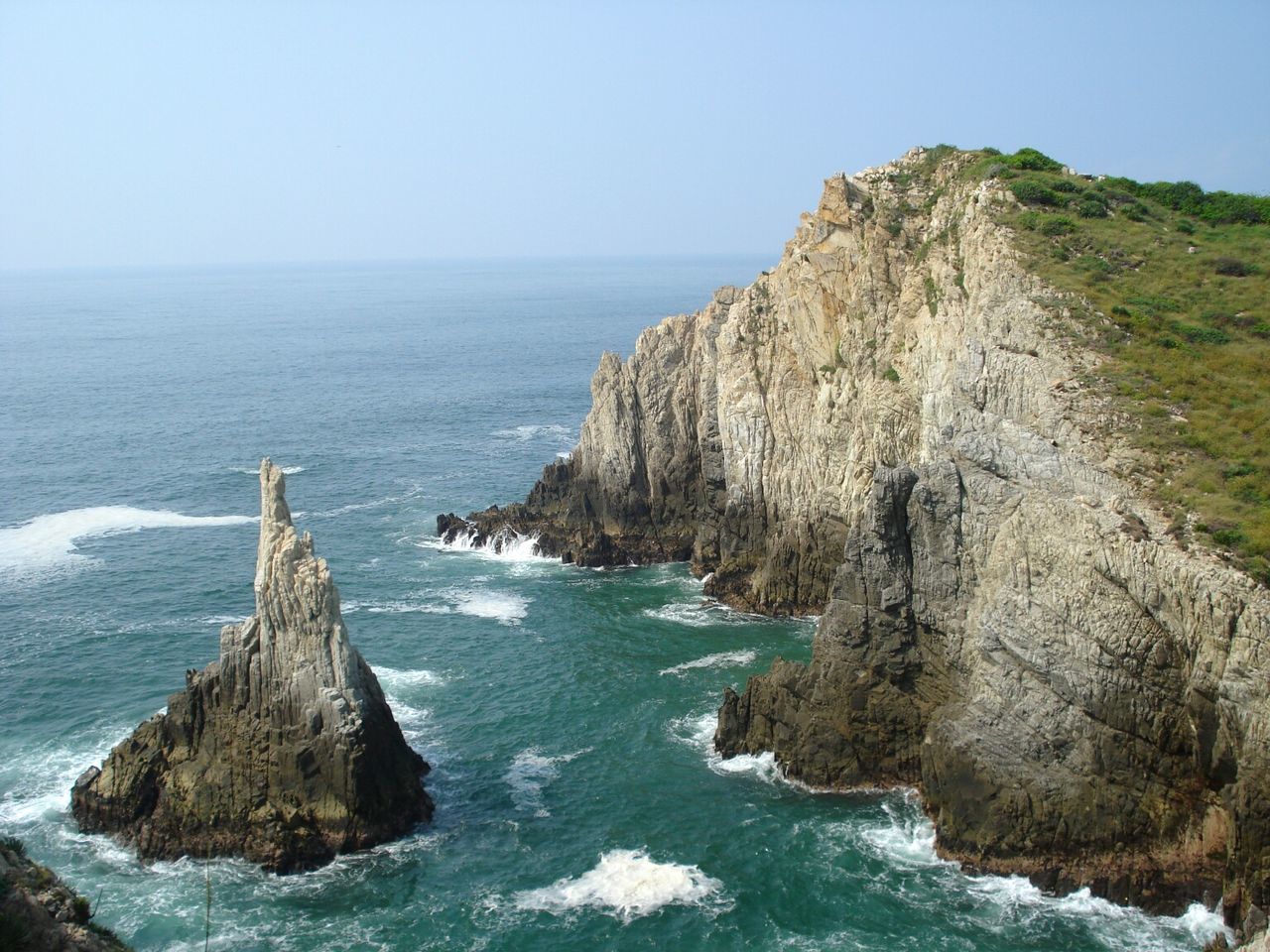 Scenic view of rocky mountains by sea against clear sky