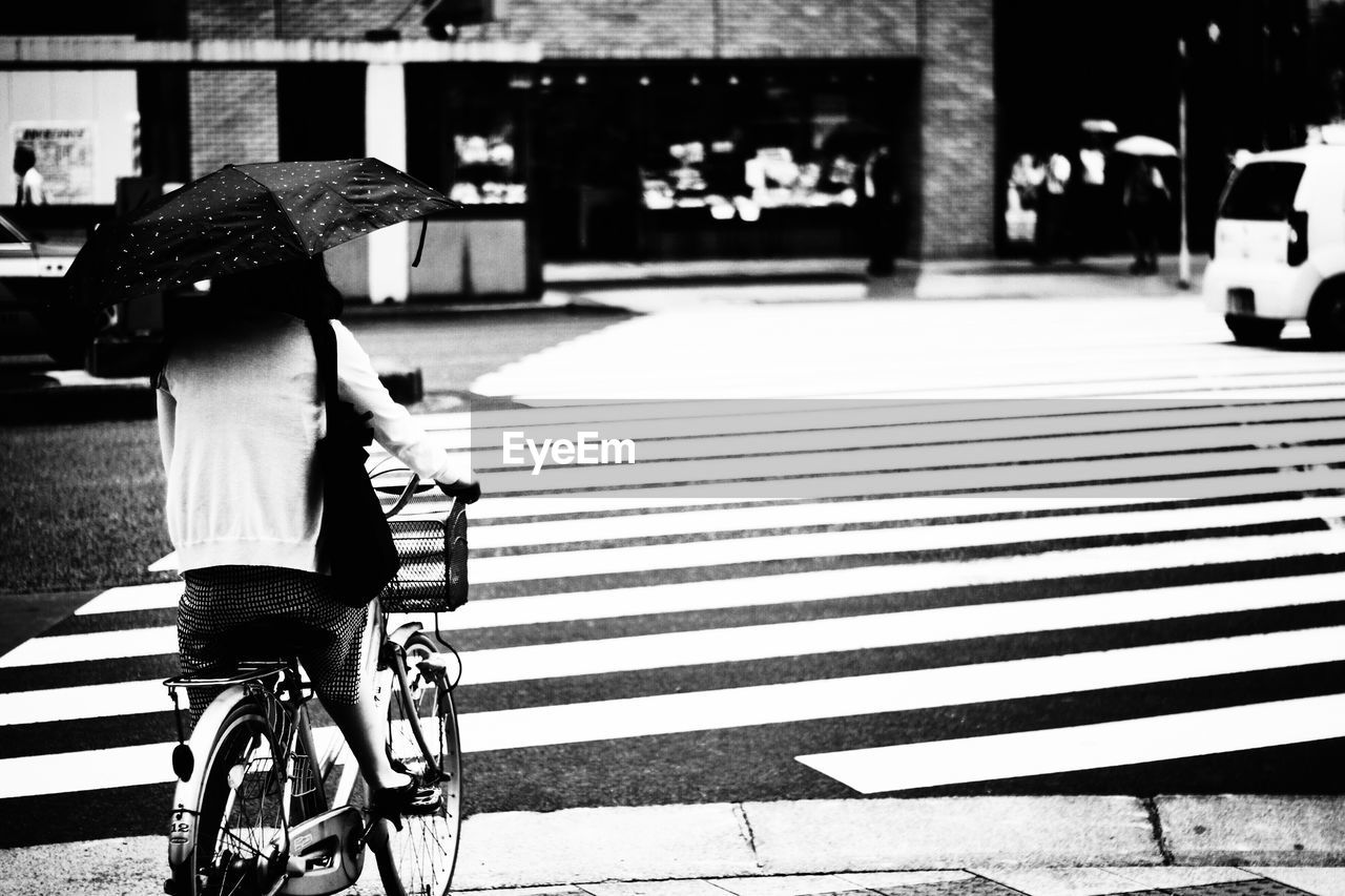 Rear view of woman with bicycle walking on road