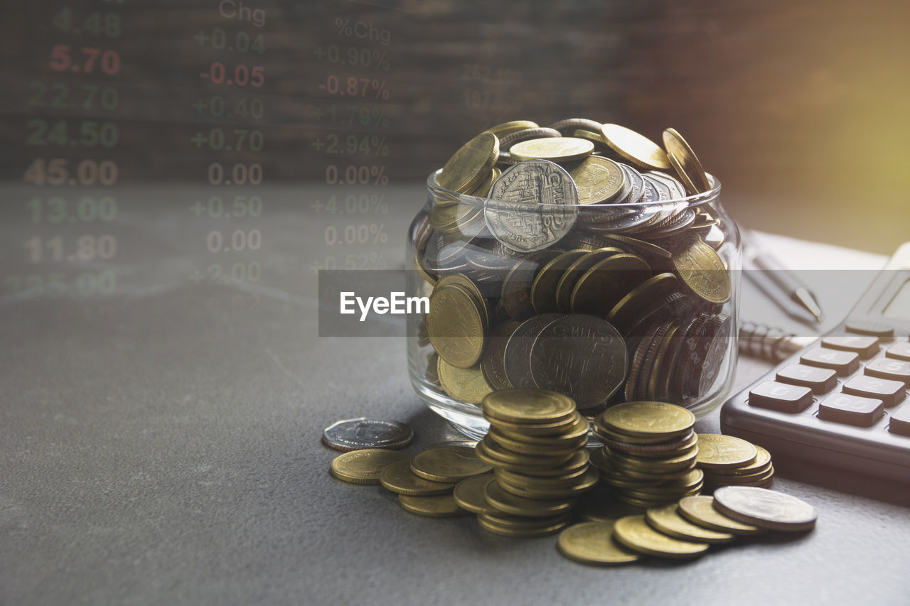 Double exposure of financial figures and coins on table