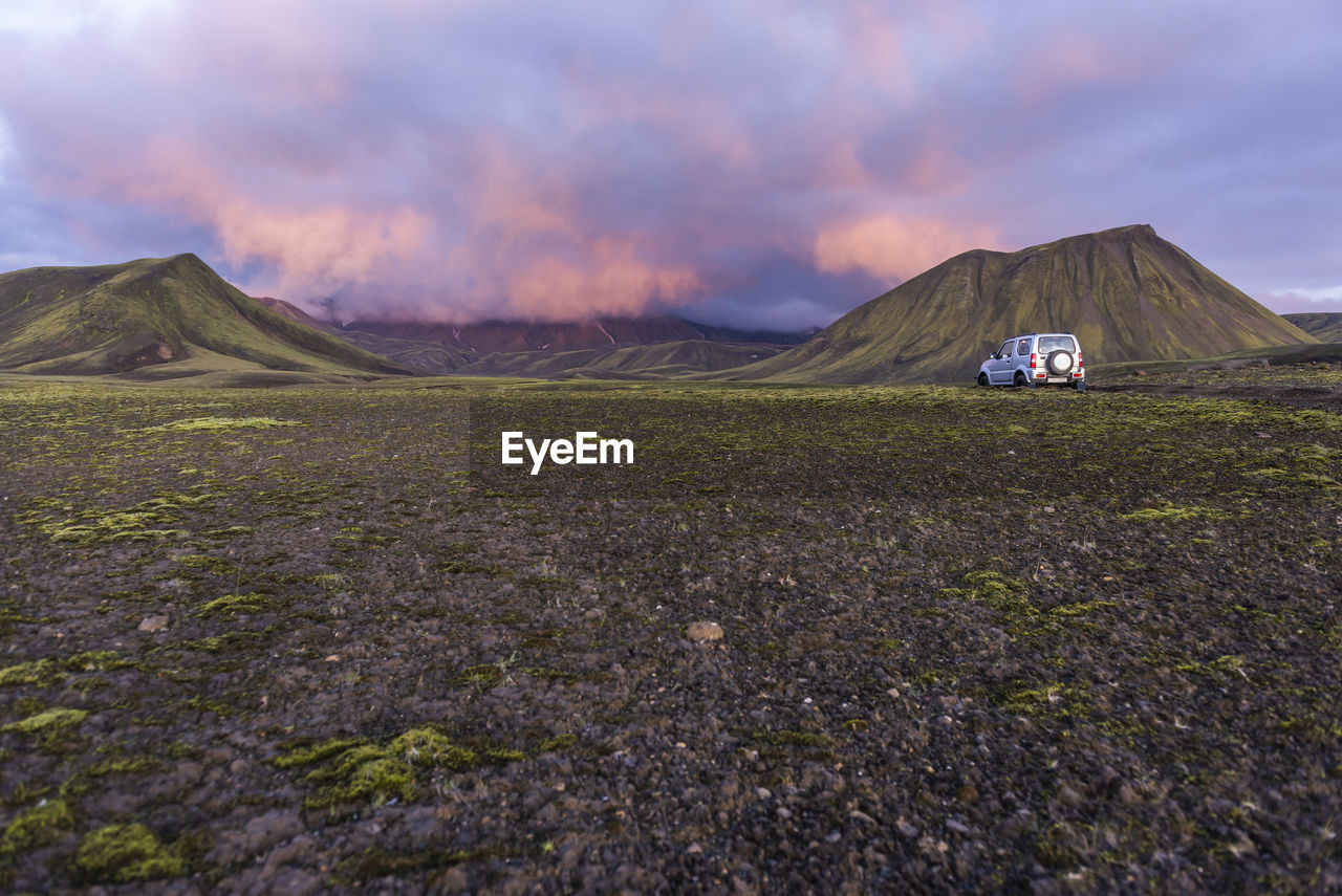 View from back of small 4x4 driving toward mountains at sunset