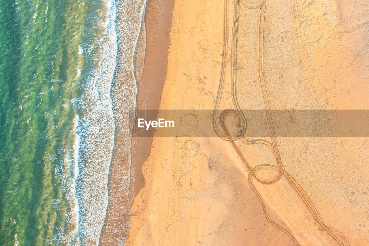 Aerial view of beach with tire tracks on sand. turquoise sea and golden sand. 